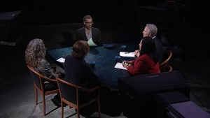 A group of people sitting around a table in front of a camera.