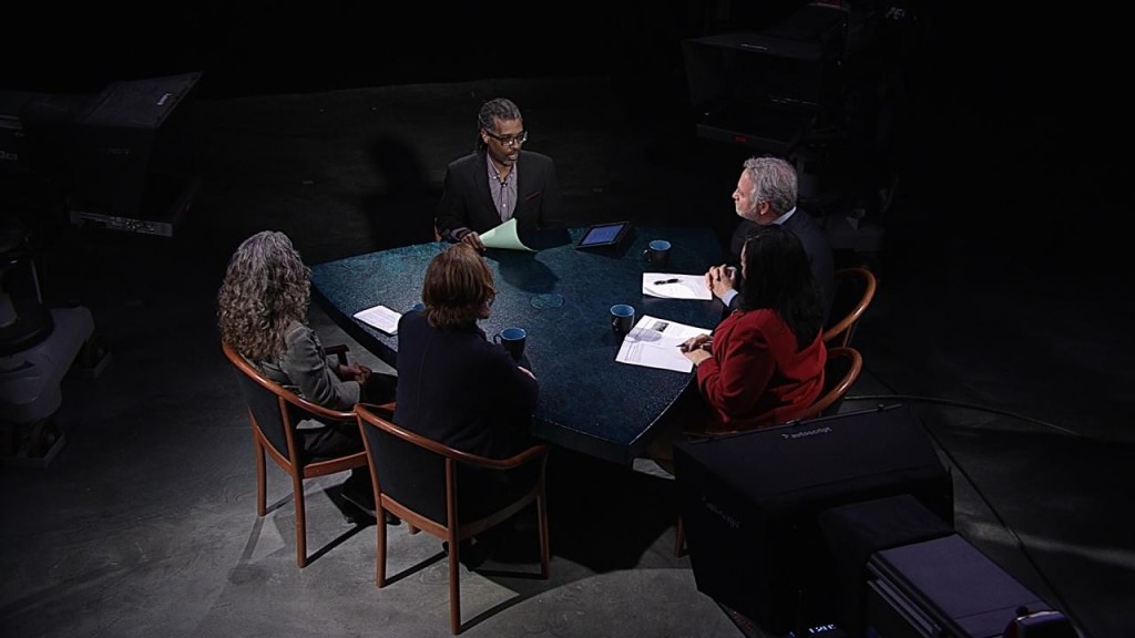 A group of people sitting around a table in a dark room.