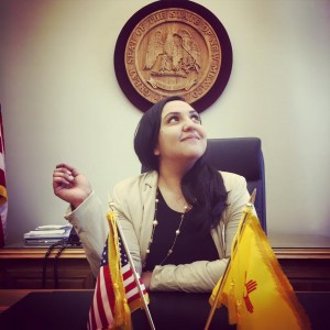 A woman sitting at a desk with flags in front of her.