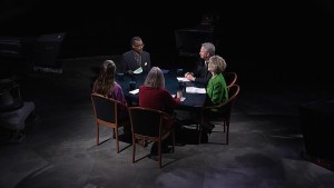 A group of people sitting around a table in a dark room.