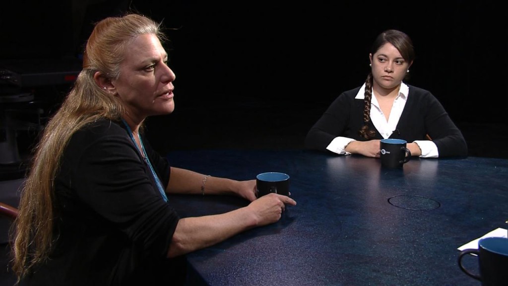 Two women sitting at a table talking to each other.