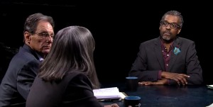 Three people sitting at a table talking to each other.