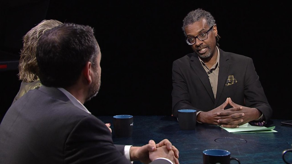 Two men sitting at a table talking to each other.