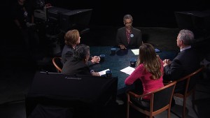 A group of people sitting at a table in front of a camera.