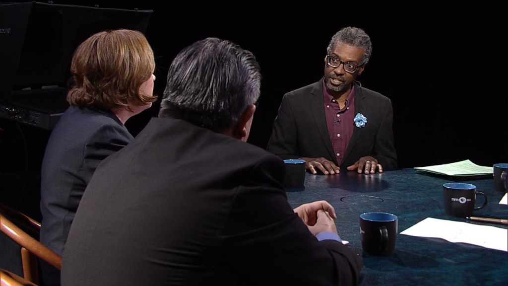 Three people sitting at a table talking to each other.