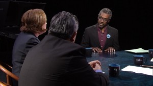 Three people sitting at a table talking to each other.