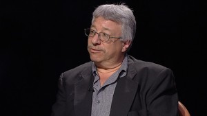 A man in glasses sitting in a chair.