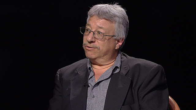A man in glasses sitting in a chair.