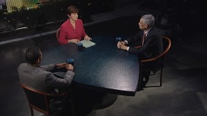 Three people sitting at a table in front of a city.