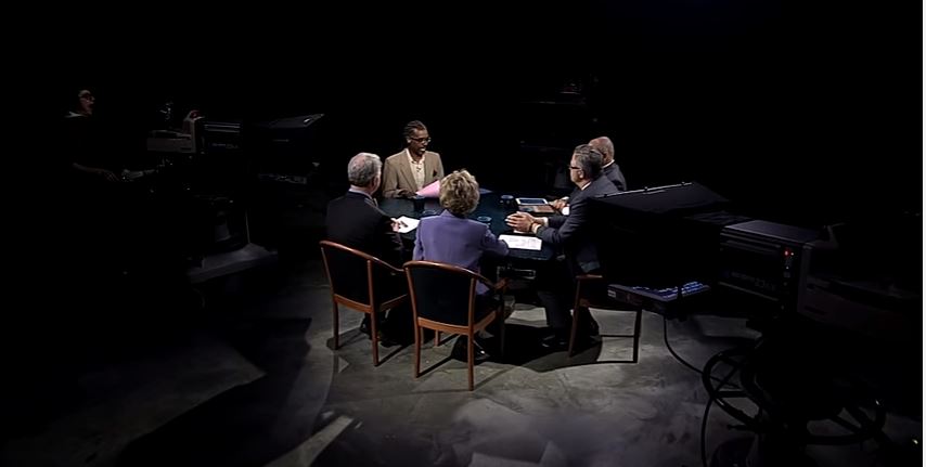 A group of people sitting around a table in a dark room.