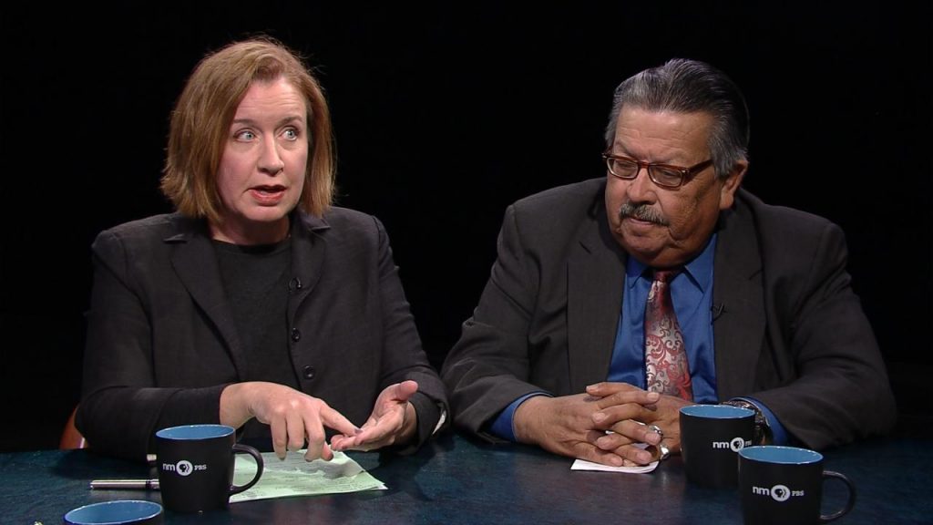 A man and woman sitting at a table with a cup of coffee.