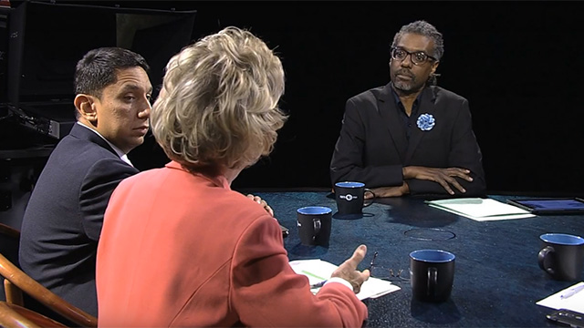 Three people sitting at a table talking to each other.