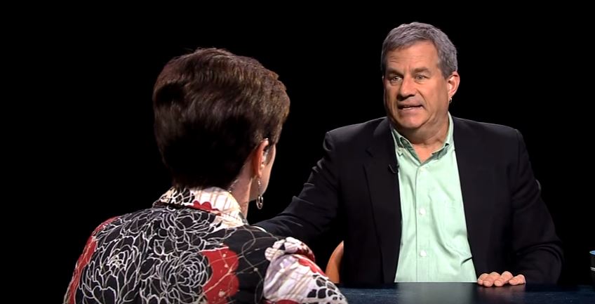 A man and woman sitting at a table talking.