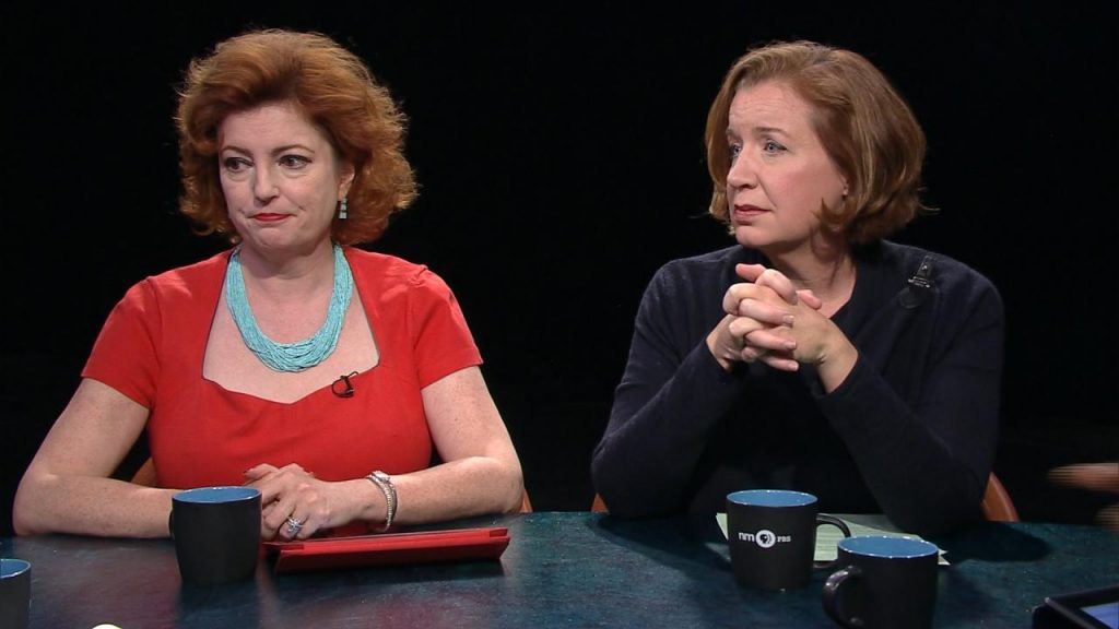 Two women sitting at a table talking to each other.