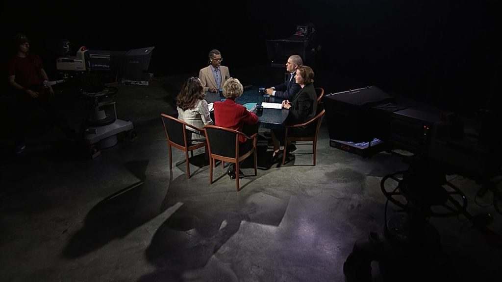 A group of people sitting around a table in a dark room.