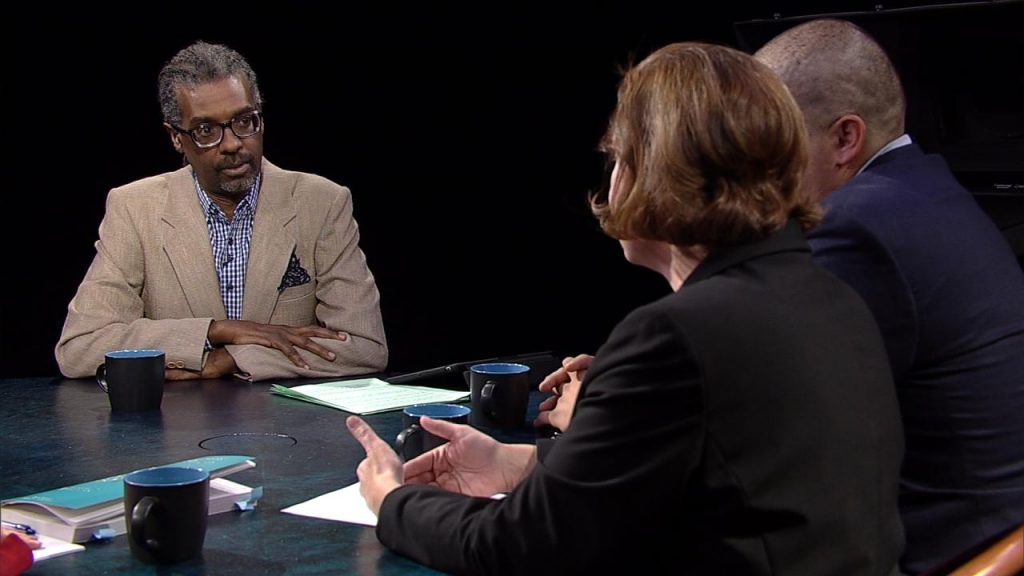 Three people sitting at a table talking to each other.