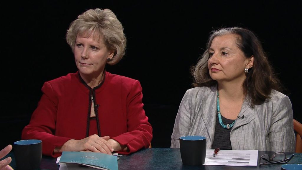 Three women sitting at a table talking to each other.