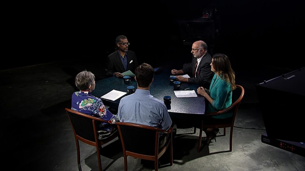 A group of people sitting around a table in a dark room.