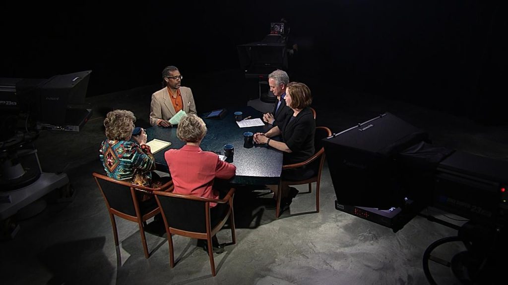 A group of people sitting around a table in a dark room.