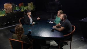 A group of people sitting around a table in a television studio.