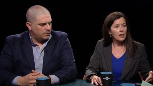 A man and woman sitting at a table talking.