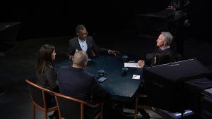 A group of people sitting around a table in a studio.