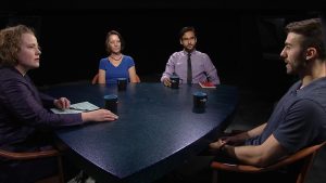 A group of people sitting around a table talking.