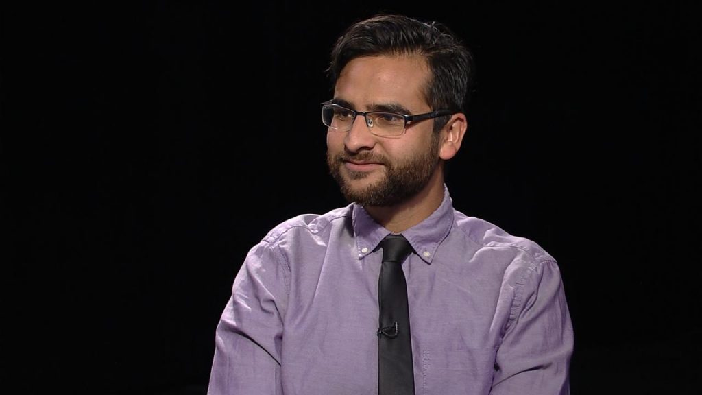 A man wearing glasses and a purple shirt.