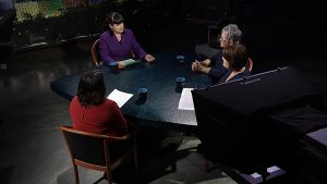 Three women sitting around a table in a television studio.