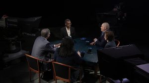 A group of people sitting around a table in a dark room.