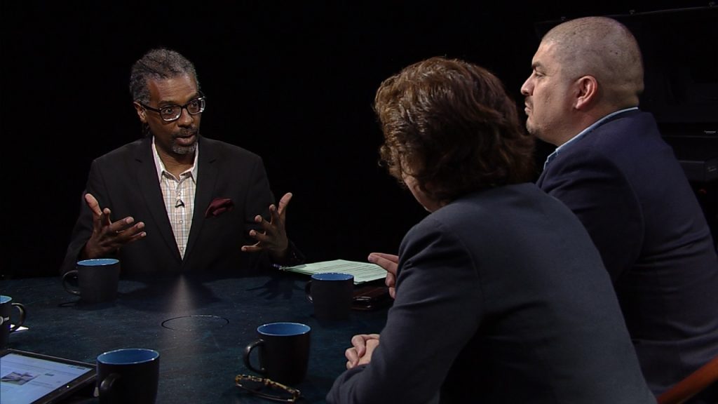 Three people sitting around a table talking.