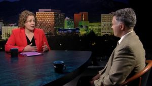 A man and woman sitting at a table in front of a city.
