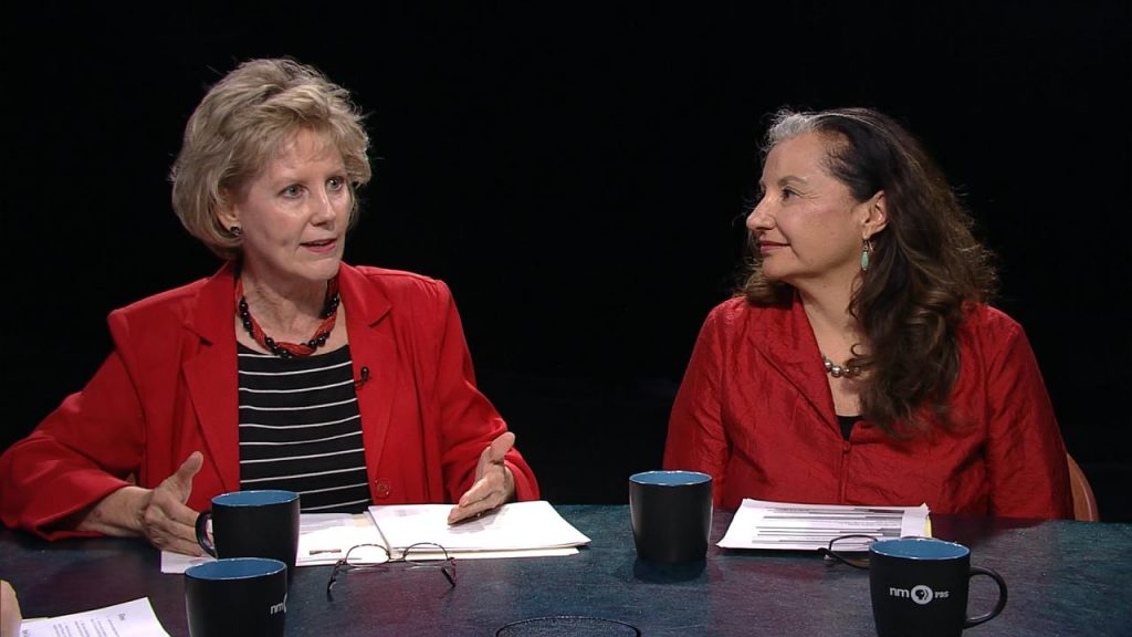 Three women sitting at a table talking to each other.