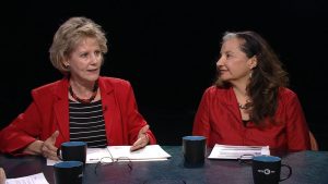 Three women sitting at a table talking to each other.