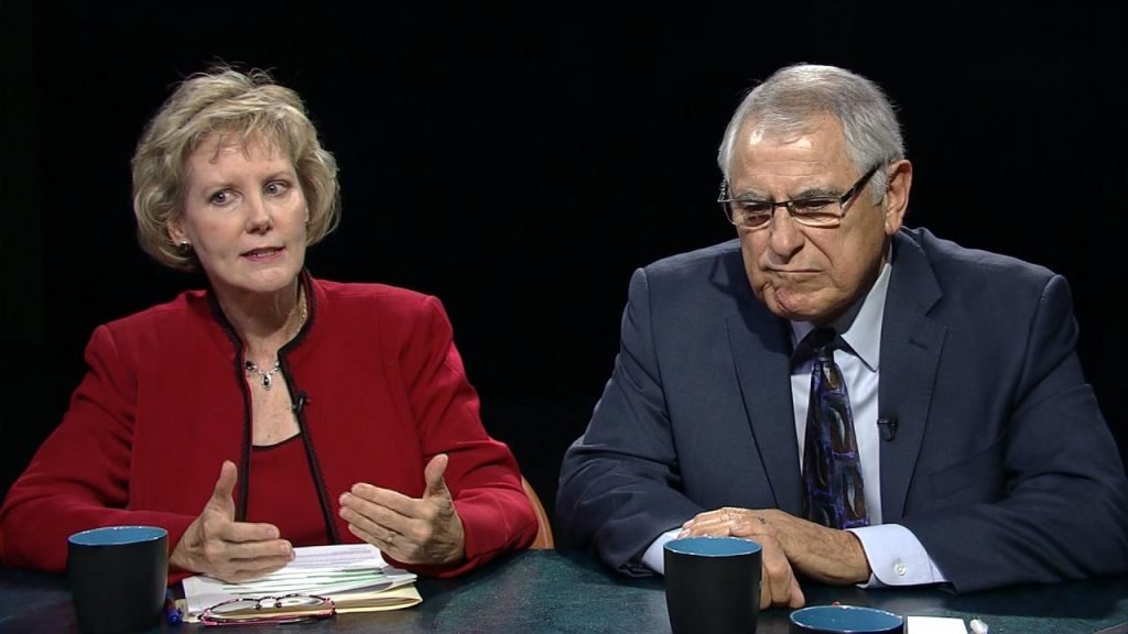 Two people sitting at a table talking to each other.