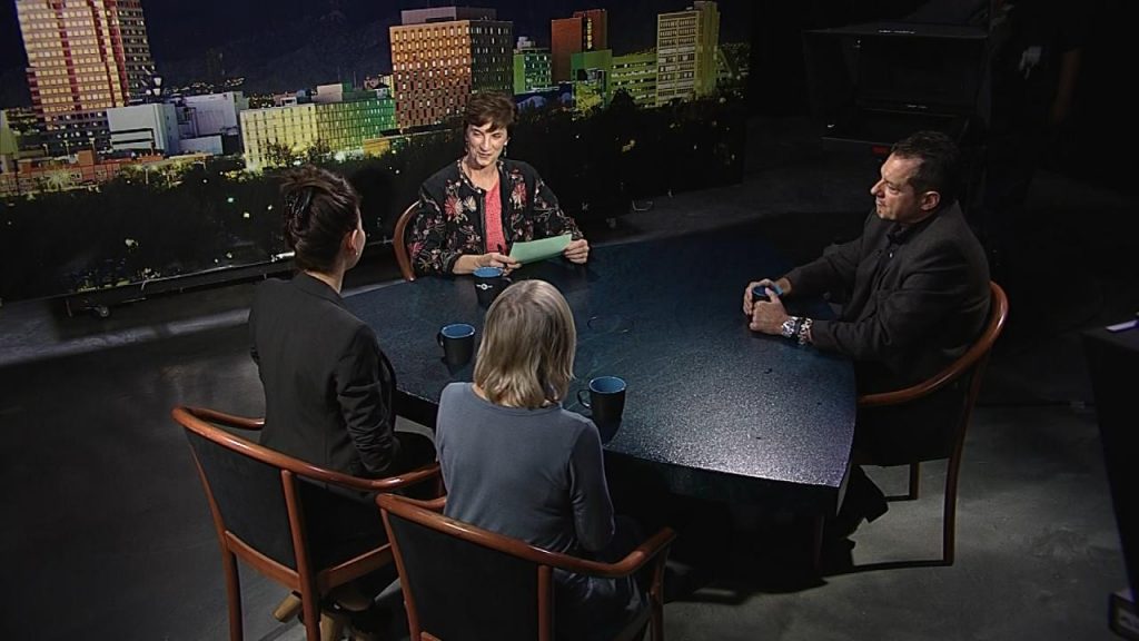 Three people sitting at a table in front of a city.