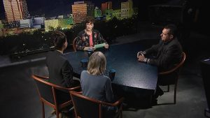 Three people sitting at a table in front of a city.
