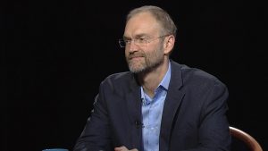 A man in glasses sitting in a chair.