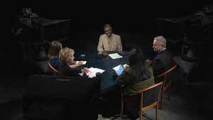 A group of people sitting around a table in a dark room.