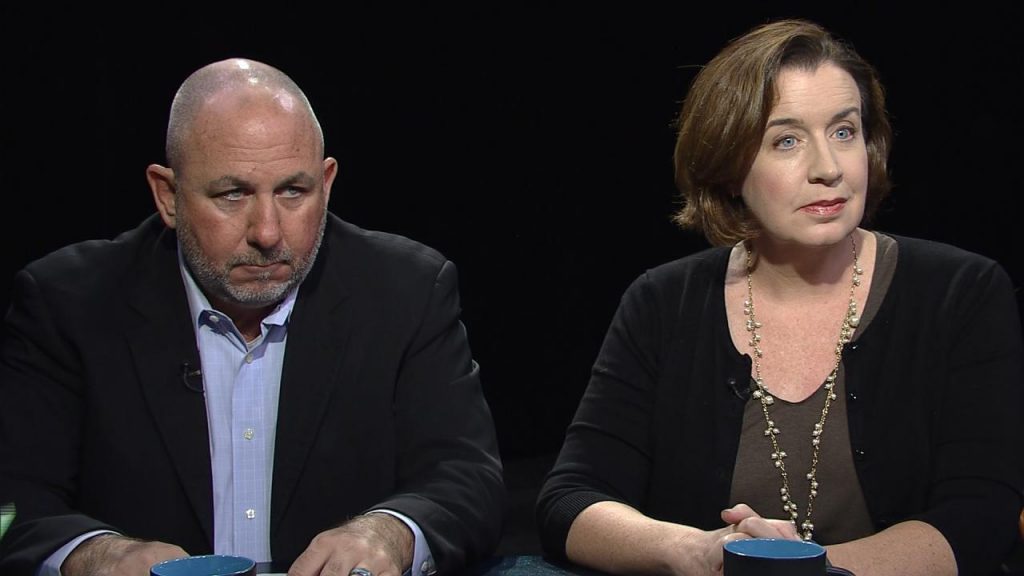 Two people sitting at a table with a cup of coffee.