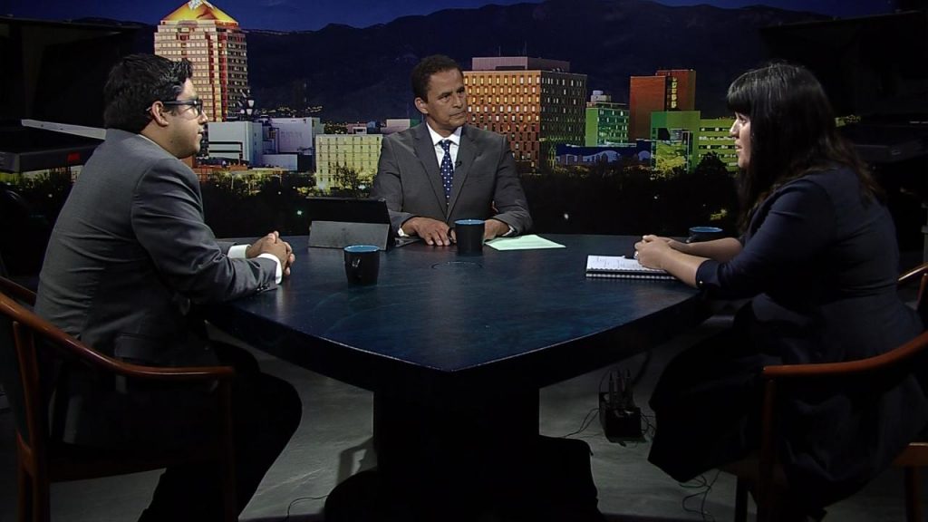 Three people sitting at a table in front of a city.