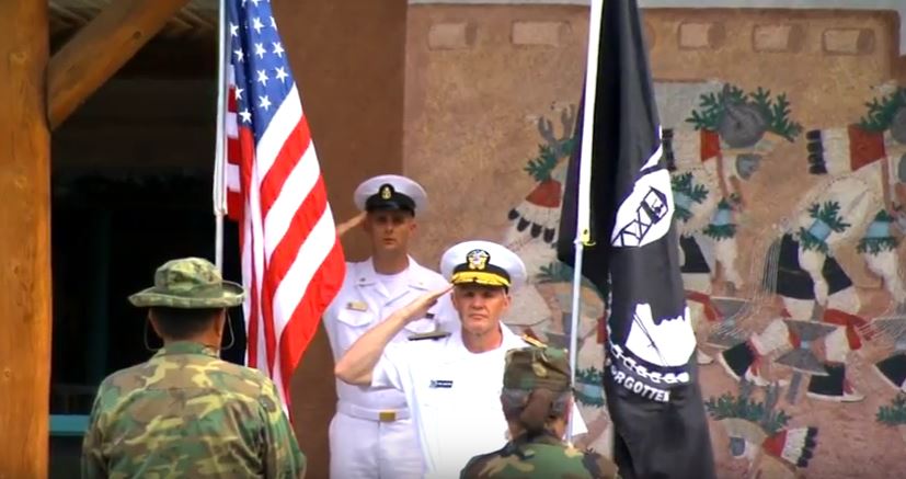 A group of military men salute the flags of the united states and mexico.