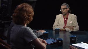 Two people sitting at a table talking to each other.