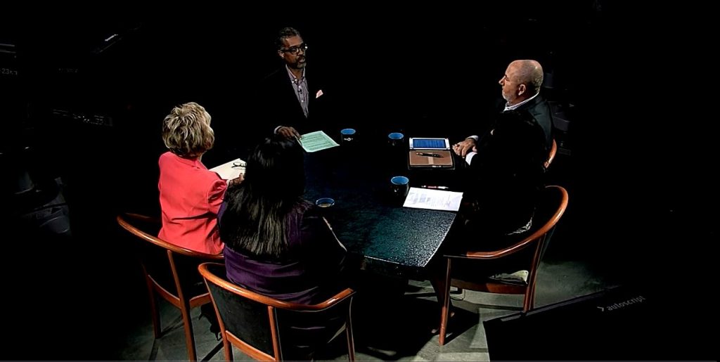 A group of people sitting around a table in a dark room.