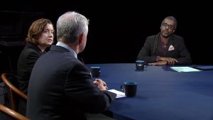 Three people sitting at a round table talking.