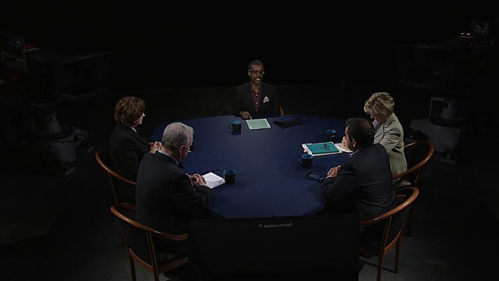 A group of people sitting around a table in a dark room.