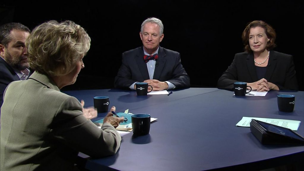 Four people sitting at a round table talking.