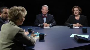 Four people sitting at a round table talking.