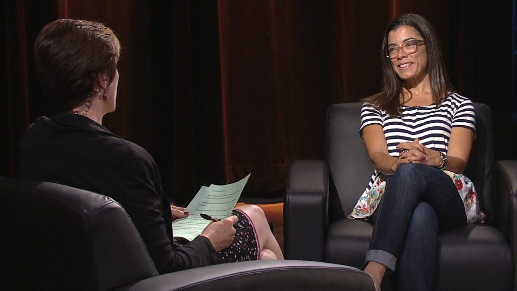 A woman sitting in a chair talking to another woman.