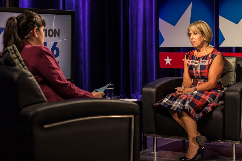 Two women sitting in chairs talking on a television.